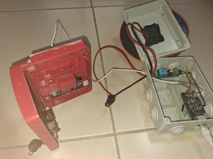 Caja de control con el ESP32-S3 y relé conectada a una sirena estroboscópica y a un pulsador de incendios rojo