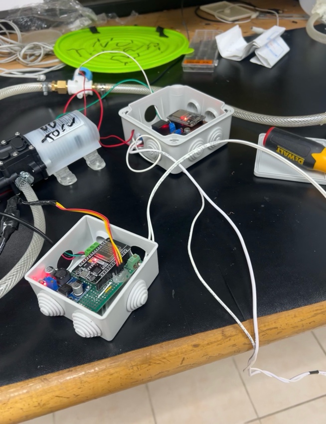 Prototipo: cajas de conexión con ESP32 y placas de control junto a una bomba de agua y mangueras
